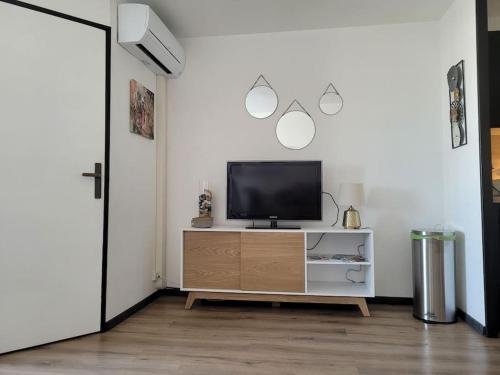un salon avec une télévision sur un meuble dans l'établissement Appartement en résidence avec vue et accès au port, à Gruissan