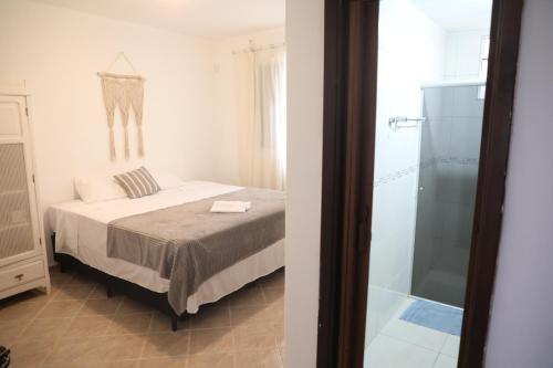 a bedroom with a bed and a glass shower at Apartamento amplo e confortável 1 in Maringá