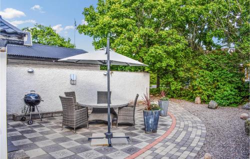 博里霍尔姆Gorgeous Home In Borgholm With Wifi的庭院配有带遮阳伞和椅子的桌子