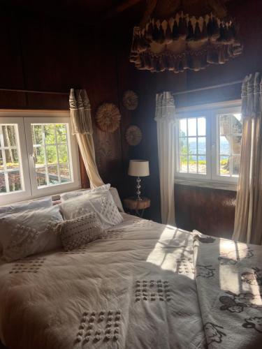 a bedroom with a large white bed with windows at Quinta da Hortigueira - Country House in Trancoso
