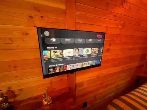 a flat screen tv hanging on a wooden wall at Heerlijk vertoeven achter de groentetuin in Epe