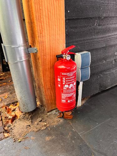 a red fire hydrant sitting next to a building at Heerlijk vertoeven achter de groentetuin in Epe