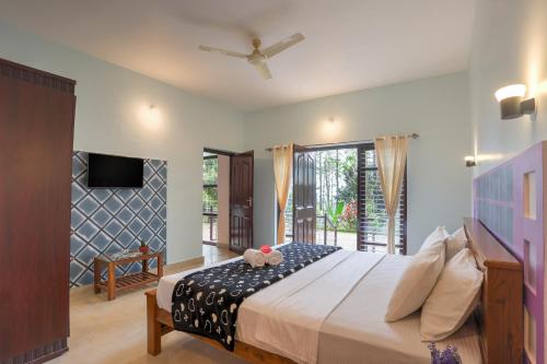 a bedroom with a large bed and a tv at Royal Woods Coorg in Madikeri