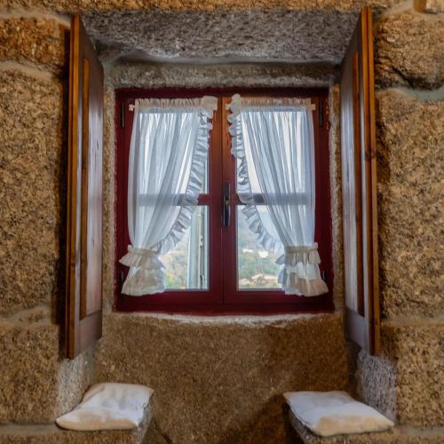 a window with white curtains in a stone wall at Quinta das Netas in Cabeceiras de Basto