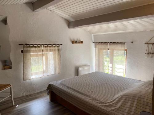 une chambre avec un lit et deux fenêtres dans l'établissement Gîte de 2 ou 3 personnes la Bergerie, à Gravières