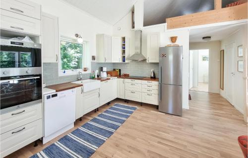 a kitchen with white cabinets and a stainless steel refrigerator at Stunning Home In Tvärred With Kitchen in Alhammar
