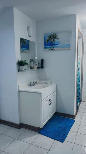 a white kitchen with a sink and a blue rug at CosyRoom in Brossard