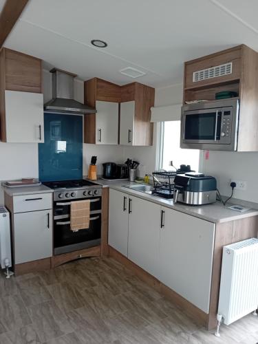 a kitchen with a stove and a microwave at Caravan in Jaywick,Jaywick sand, Clacton-on-sea in Jaywick Sands