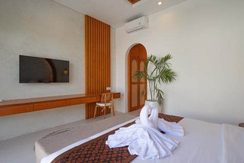 a hotel room with a bed with a tv on the wall at The Adya Hidden Villa Ubud in Ubud