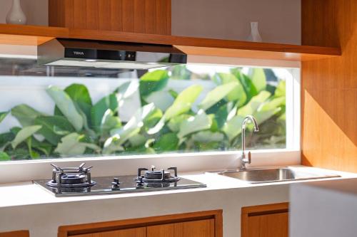 a kitchen counter with a sink and a window at The Adya Hidden Villa Ubud in Ubud