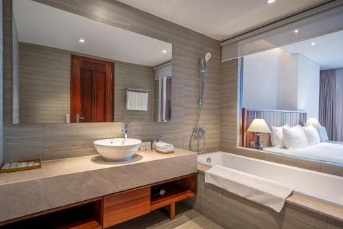 a bathroom with a sink and a tub and a bed at Green Beach Hotel Nha Trang in Nha Trang