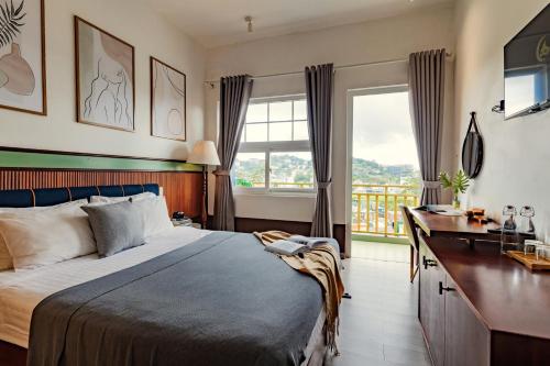 una camera da letto con un letto, una scrivania e una finestra di Casanova Dalat Hotel a Da Lat