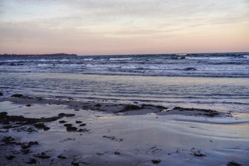a beach with waves and a boat in the ocean at Kuschelige Herbsttage und Meeresrauschen in Breege