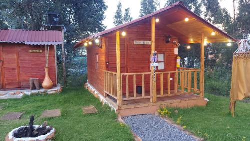 a wooden cabin with a porch in the grass at Cabaña campestre #1 in Ráquira