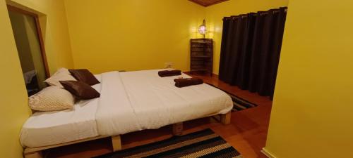 a bedroom with a bed with white sheets and brown pillows at Zimr in Coonoor
