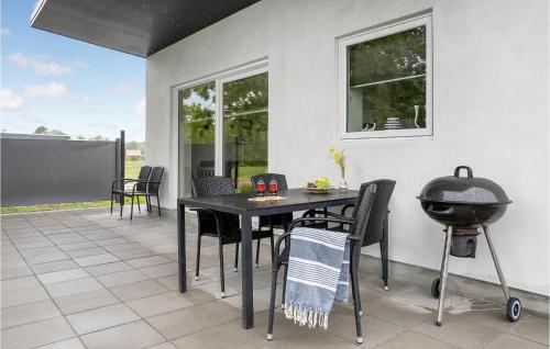 eine Terrasse mit einem Tisch, Stühlen und einem Grill in der Unterkunft Lovely Home In Ringkøbing With Kitchen in Hee