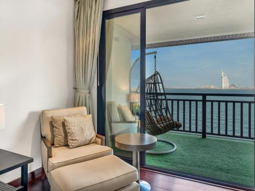 a room with a chair and a balcony with a swing at Luxury Apartments in Anantara Resort with Stunning Burj AlArab & Sea Views in Dubai