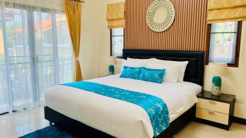 a bedroom with a large bed with blue pillows at Malinee Villa Phuket in Bang Tao Beach