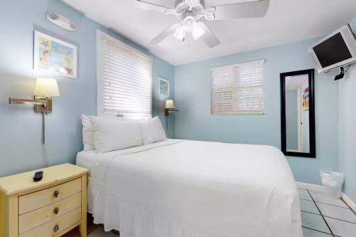 Un dormitorio con una cama blanca y un ventilador de techo. en Duval Street Retreat, en Key West
