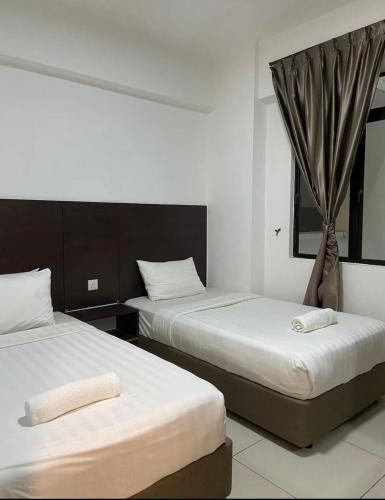 two beds in a hotel room with a window at Marina Heights Apartment in Lumut