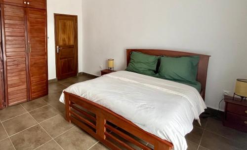 a bedroom with a large bed with green sheets at Résidence Créolia in Kribi