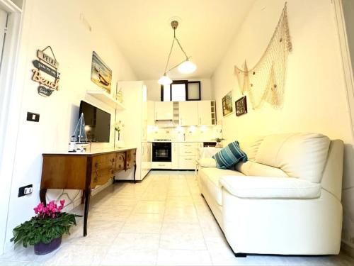 a living room with a white couch and a kitchen at Casa Marilyn in Ascea