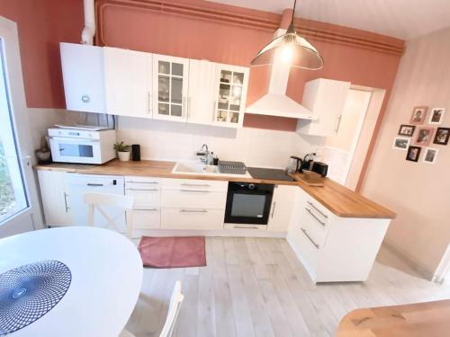 a kitchen with white cabinets and a sink at Charmante maison familiale -Jardin -WIFI -Parking in Mérignac