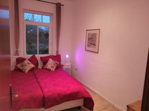 a bedroom with a red bed with a window at Casa Linda in Rotenburg an der Wümme