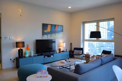 a living room with a blue couch and a tv at Elegant Reem Atelier - 2BR Urban Escape in Abu Dhabi
