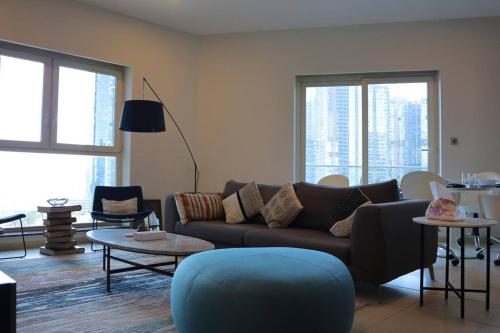 a living room with a couch and tables and windows at Elegant Reem Atelier - 2BR Urban Escape in Abu Dhabi