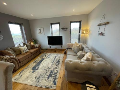 a living room with a couch and a flat screen tv at Switha - Luxury home in Stromness, Orkney with outstanding views and hot tub in Orkney