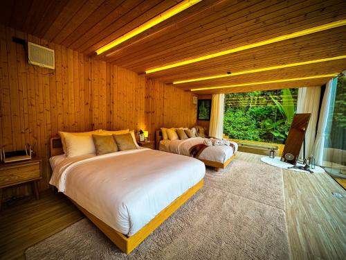 a bedroom with two beds and a large window at Morning Star Glamping in Ban Pok Nai