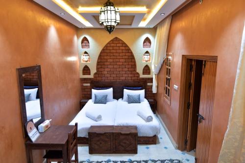 a bedroom with a bed and a table and a lamp at Dar Chams Ouarzazate in Ouarzazate