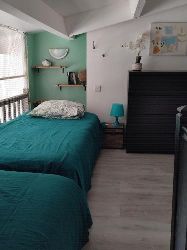 une chambre avec un lit vert et une fenêtre dans l'établissement Cap d'Agde duplex l'Olivier vue mer 5 à 6 pers, au Cap d'Agde