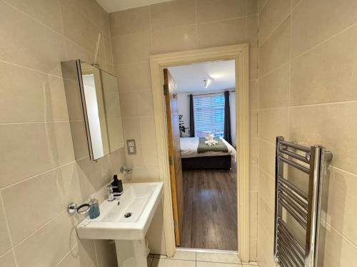 a bathroom with a sink and a mirror and a bedroom at Modern TWO Bedroom Apartment Birmingham City Centre - 2 BATHROOMS - SLEEPS 6 GUESTS - FREE Underground Parking - FAST Speed Internet in Birmingham