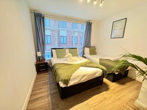 a bedroom with two beds and a window at Modern TWO Bedroom Apartment Birmingham City Centre - 2 BATHROOMS - SLEEPS 6 GUESTS - FREE Underground Parking - FAST Speed Internet in Birmingham