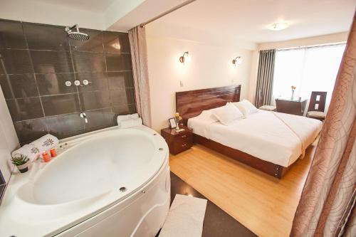 a bathroom with a bath tub and a bed at Inti Tampu Inn in Cusco