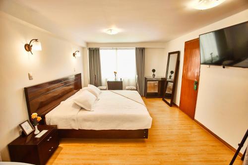 a hotel room with a bed and a flat screen tv at Inti Tampu Inn in Cusco