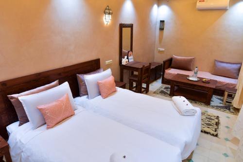 a bedroom with two beds and a chair and a table at Dar Chams Ouarzazate in Ouarzazate