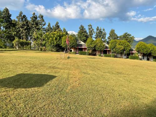 a large grass field with houses in the background at Bansuan viewpai in Pai