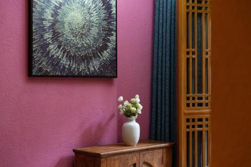 a vase of flowers sitting on a table next to a wall at Gucheng Lanshe Designer Garden B&B in Lijiang