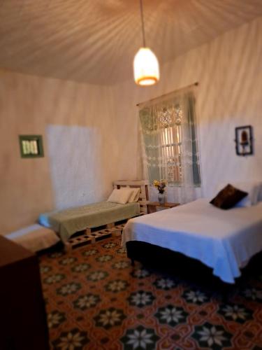 a bedroom with two beds and a couch and a window at Hostal Prana in Abejorral