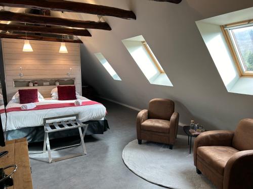 a attic bedroom with a bed and two chairs at Logis Hôtel de Paris in Murol