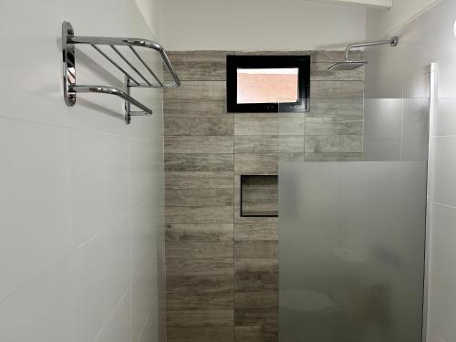 ein Badezimmer mit einem Fernseher an der Wand und einer Dusche in der Unterkunft cabañas La Amelia Premium con piscina privada 2 personas in Mina Clavero