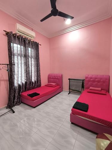 a pink room with two beds and a ceiling fan at Tiffana Homestay in Kampong Ayer Terjun