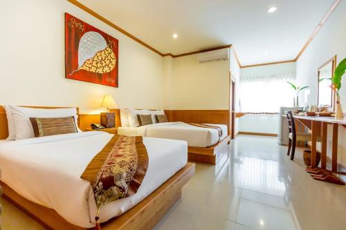 a hotel room with two beds and a desk at Loei Village Hotel in Loei