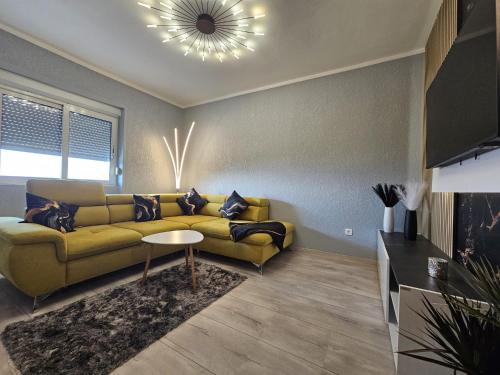a living room with a yellow couch and a table at Apartmani Višnja in Crikvenica