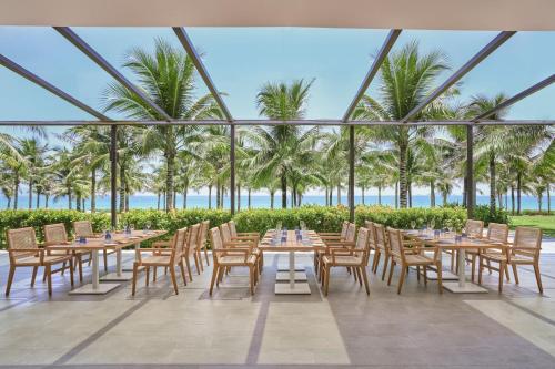 a restaurant with tables and chairs and palm trees at The Westin Resort & Spa Cam Ranh in Cam Ranh