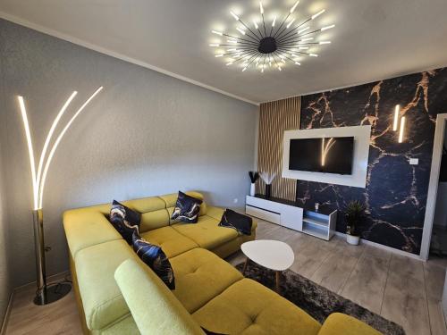 a living room with a yellow couch and a tv at Apartmani Višnja in Crikvenica