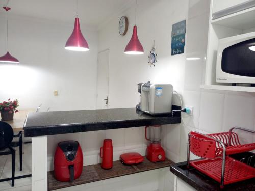 a kitchen with a counter with a microwave and red chairs at Um luxo de apartamento na Enseada in Guarujá